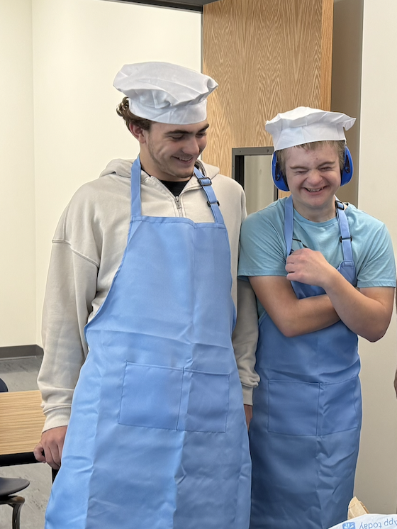 Two Unified Culinary Students in aprons and hairnets smiling